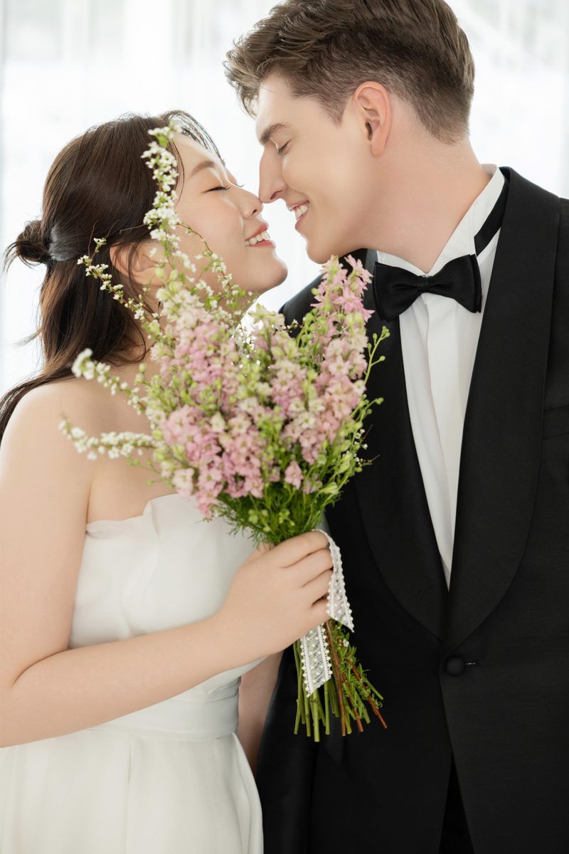 Leah and Nathan nose to nose behind a bouquet
